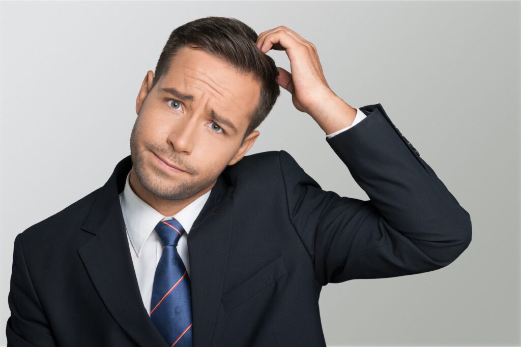 Confused man in suit scratching his head.