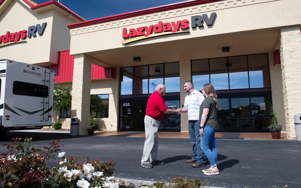 RV sellers shaking hands with RV buyer outside of dealership