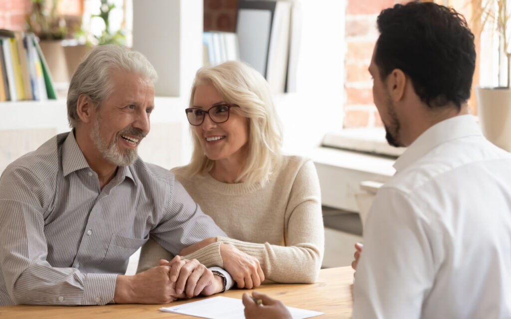 Couple smiling while talking to RV buyer over paperwork